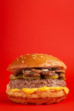 Kırmızı arka planda lezzetli bir burger. Peynirli lezzetli ve sağlıksız hamburgerler. Fast food, abur cubur kavramı.