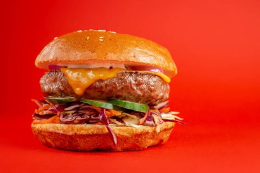 Kırmızı arka planda lezzetli bir burger. Peynirli lezzetli ve sağlıksız hamburgerler. Fast food, abur cubur kavramı.
