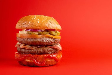 Kırmızı arka planda lezzetli bir burger. Peynirli lezzetli ve sağlıksız hamburgerler. Fast food, abur cubur kavramı.