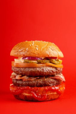 Kırmızı arka planda lezzetli bir burger. Peynirli lezzetli ve sağlıksız hamburgerler. Fast food, abur cubur kavramı.