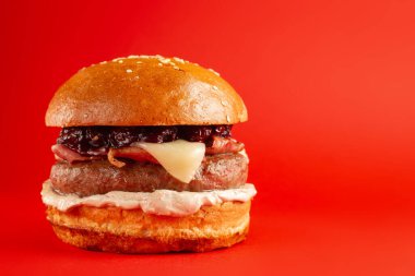 Kırmızı arka planda lezzetli bir burger. Peynirli ve iki köfteli leziz sağlıksız burger. Fast food, sağlıksız gıda konsepti.