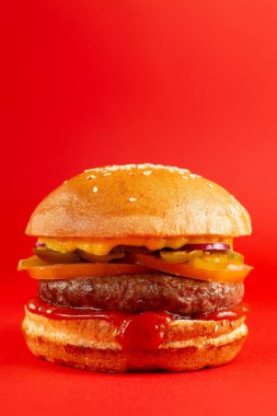 Kırmızı arka planda lezzetli bir burger. Peynirli ve iki köfteli leziz sağlıksız burger. Fast food, sağlıksız gıda konsepti.