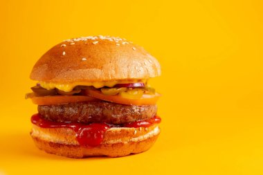 Sarı arka planda lezzetli bir burger. Peynirli ve iki köfteli leziz sağlıksız burger. Fast food, sağlıksız gıda konsepti.