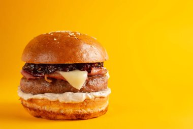 Sarı arka planda lezzetli bir burger. Peynirli ve iki köfteli leziz sağlıksız burger. Fast food, sağlıksız gıda konsepti.