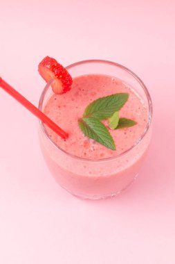 Pembe arka planda naneli çilekli milkshake. Kahvaltıda ve atıştırmalıklarda sağlıklı yemek.