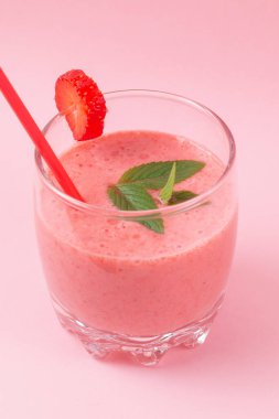 Pembe arka planda naneli çilekli milkshake. Kahvaltıda ve atıştırmalıklarda sağlıklı yemek.