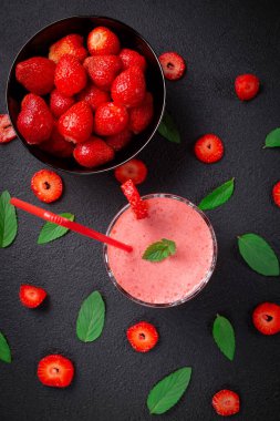 Çilekli milkshake, koyu taşlı arka planda naneli bardakta. Kahvaltıda ve atıştırmalıklarda sağlıklı yemek..