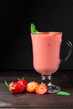 Koyu arkaplanda böğürtlenlerle süslenmiş taze çilekli milkshake. Sağlıklı kahvaltı, diyet ve iyi beslenme kavramı.. 