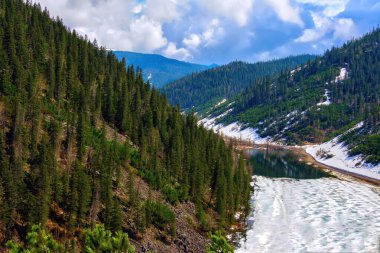 Yeşil ağaçları ve donmuş nehri olan dağların güzel manzarası