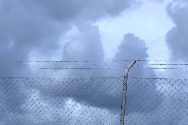 Metalik ağ kara fırtınalı bulutlara karşı gökyüzü. Umutsuzluk ve korku kavramları