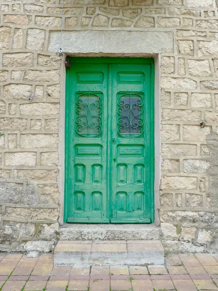 Green wooden door in Patones village, Community of Madrid. Vintage doorway in rural area of Spain