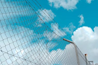 Kümülüs bulutlu mavi gökyüzüne karşı endüstriyel metalik ağ.