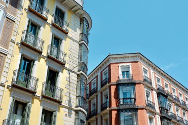 Classical yellow and red buildings with elegant metallic balconies in Chueca district downtown Madrid, Spain