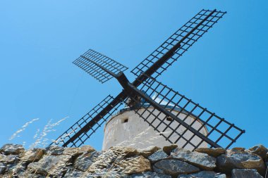 Mavi gökyüzüne tepeden tırnağa beyaz yel değirmenini izleyin. Enerji, güç ve direniş kavramları