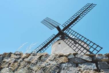 Mavi gökyüzüne karşı siyah tahta bıçakları olan beyaz yel değirmeni. Enerji, güç ve direniş kavramları