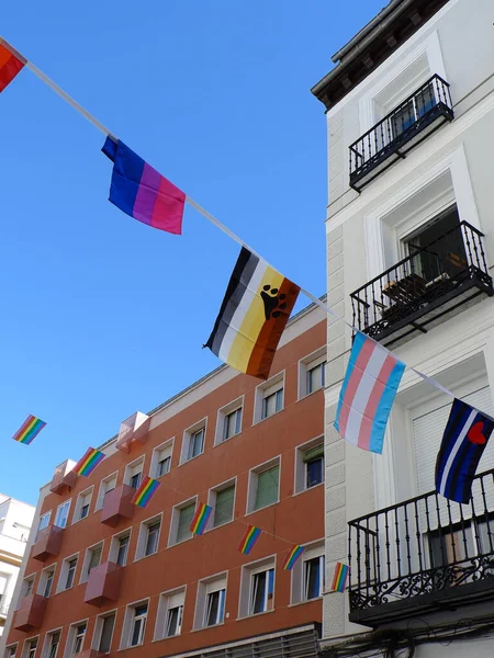 Different flags strung between buildings in gay friendly Chueca district in Madrid, Spain. LGBTQ community symbols outside on the streets downtown.