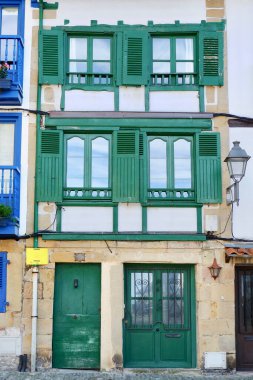 Hondarribia, Bask Bölgesi, İspanya 'da yeşil pencereli ve balkonlu canlı bir bina. Dikey fotoğraf