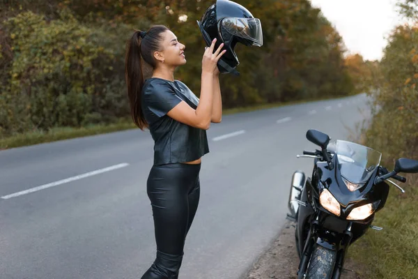 Νεαρή Γυναίκα Μοτοσικλετίστρια Βάζει Ένα Κράνος Στο Κεφάλι Της — Φωτογραφία Αρχείου