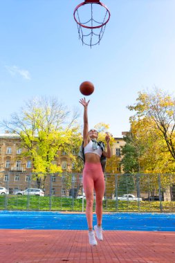 Zıplayan bayan basketbolcu topu potaya atıyor.