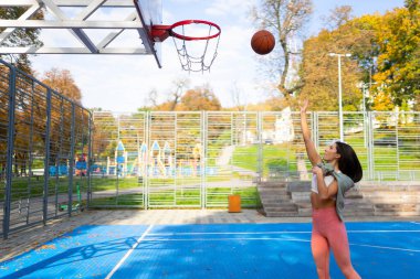 Kadın basketbolcu topu potaya atıyor.