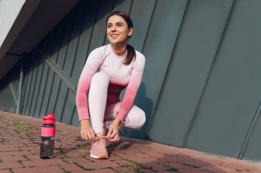 Koşan atletik kız ayakkabı bağcıklarını bağlamak için çömeldi