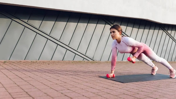 Sportos Rózsaszín Sportruházat Csinál Edzés Áll Egy Deszka Súlyzókkal Egyik — Stock Fotó