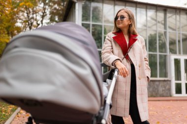 Yürüyüş için bebek arabasıyla şık bir annenin portresi.