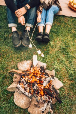 Ateşin yanında lokum kızartan çift bacakları. Piknik konsepti