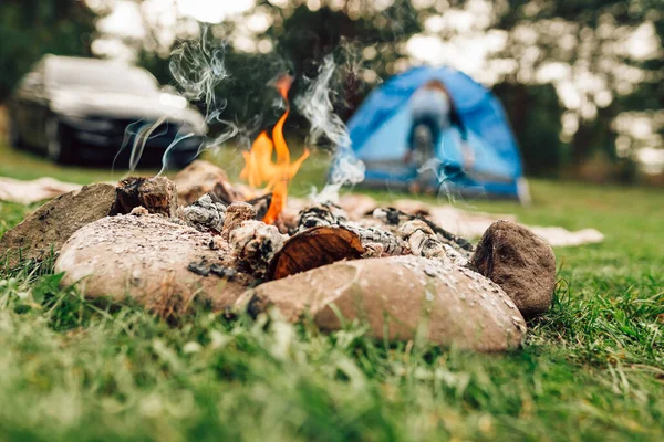 Campfire and tent with a car on its background