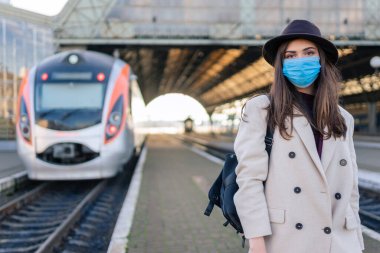 Tren istasyonunda koruyucu tıbbi maskeli bir kadın. Salgın konsepti sırasında turizm