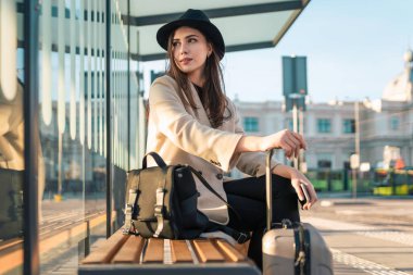 Otobüs durağında oturan kadın turist.