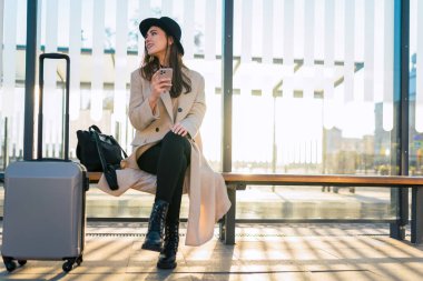 Akıllı telefonlu turist kız toplu taşımada oturur. Kız otobüs bekliyor.