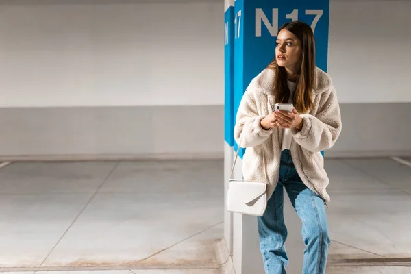 Retrato Menina Elegantemente Vestida Com Telefone Suas Mãos Estacionamento Subterrâneo — Fotografia de Stock