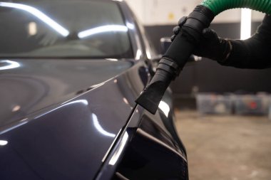 Yıkandıktan sonra araba kurutma işlemi. Elektrikli süpürgeli bir adam arabadan su damlacıklarını çıkarır. Profesyonel oto yıkama konsepti