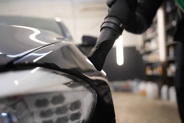 Car drying process after washing. Man with vacuum cleaner removes water droplets from car. Professional auto wash concept