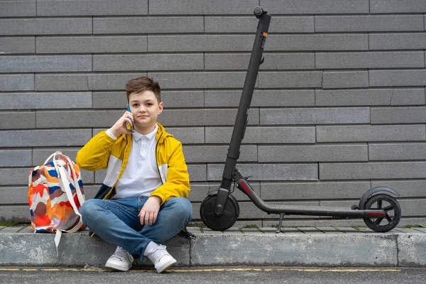 Adolescente Moderno Com Mochila Scooter Elétrico Sentado Calçada Falando Telefone — Fotografia de Stock