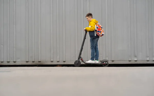 電動スクーターにバックパックの乗り物と現代のティーンエイジャー 少年は学校から戻ってくる — ストック写真