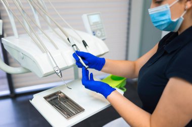 Dişçi diş matkabına burr yerleştiriyor. Doktor diş tedavisine hazırlanıyor.