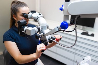 Dişçi mikroskoptan bakar. Modern diş ekipmanları