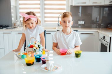 Erkek ve kız kardeşler Paskalya yumurtalarını süslerler.