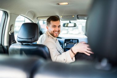 Gülümseyen adam arabanın üstünde geri geri gidiyor.