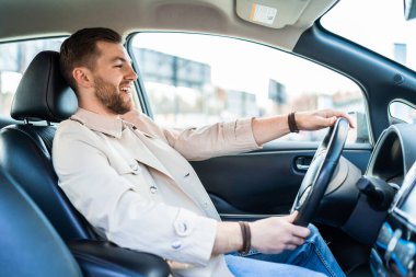 Gülümseyen yakışıklı adam araba kullanıyor.