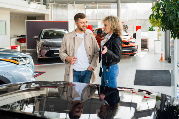 Красивая пара в автосалоне выбирает машину