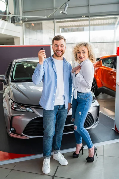 Happy couple in car dealership on the background of their new car