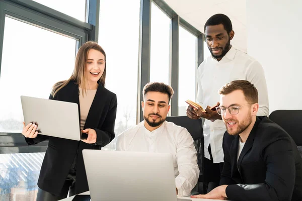Dizüstü bilgisayarın ofisinde çalışan bir grup çok ırklı iş adamı.