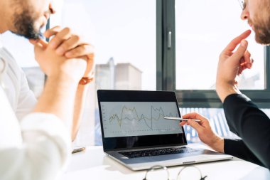 Dizüstü bilgisayardaki iki işadamı şirketin gelir artışının çizelgesini izliyor