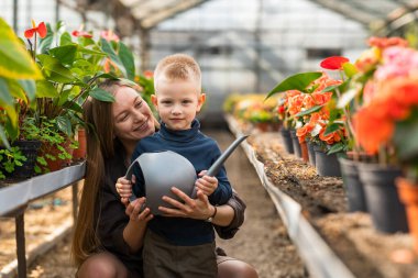 Anne ve oğlu serada bir su bidonuyla.