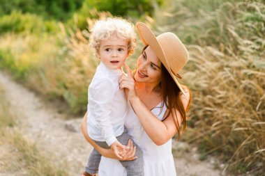 Şapkalı mutlu kadın oğluyla birlikte tarlada yürüyor.
