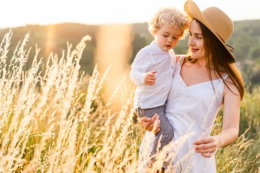 Anne ve oğlu gün batımında doğada yürüyorlar.