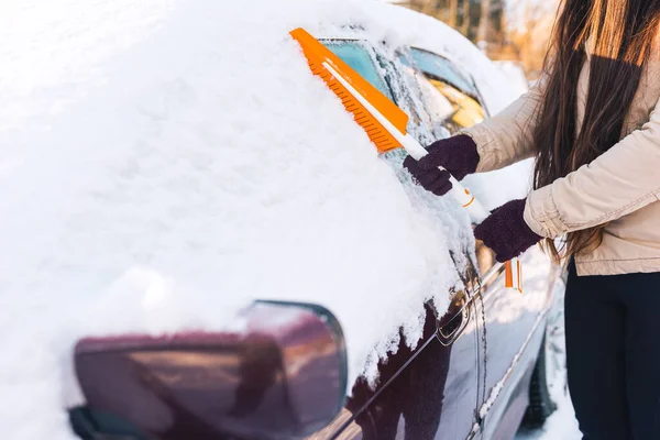 吹雪の後に雪のブラシで車をきれいにする女 ロイヤリティフリーのストック画像